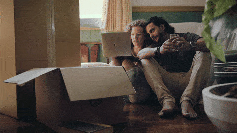 A couple with moving boxes is happy about their new apartment